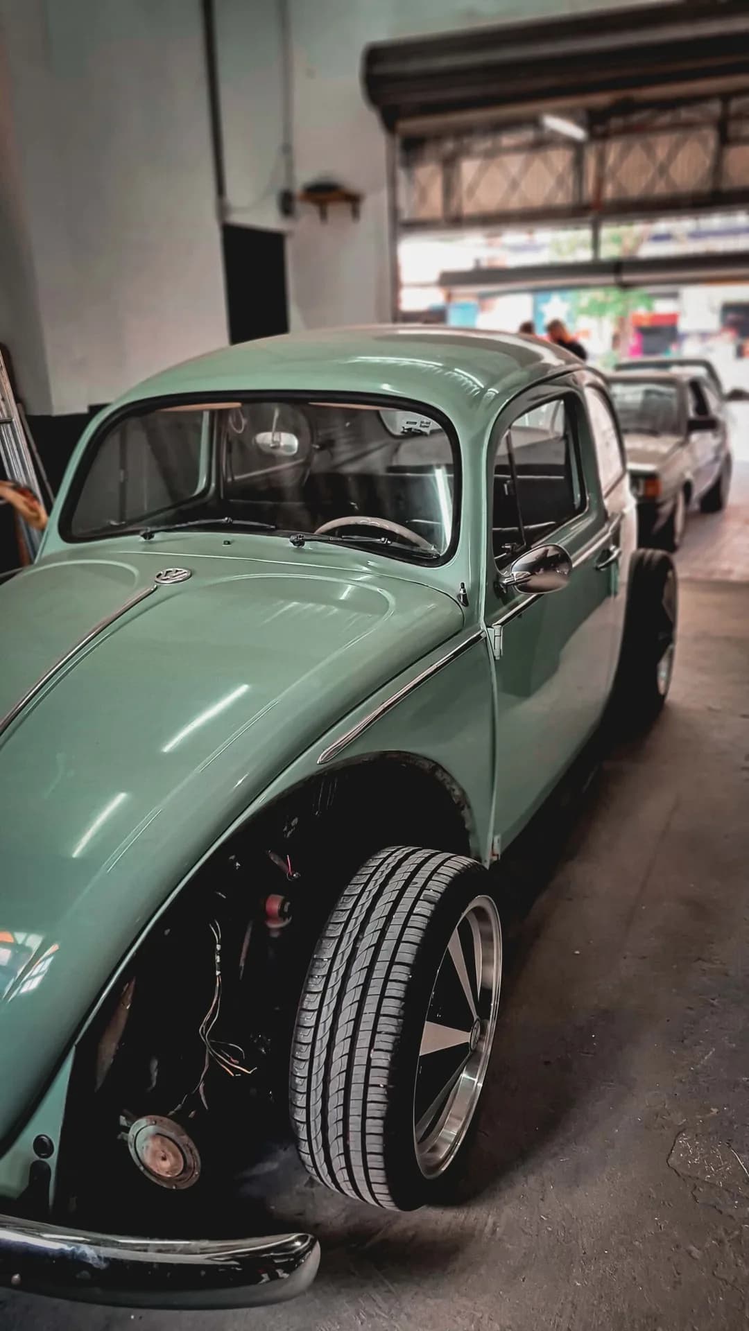 Fusca verde-claro estacionado dentro da oficina da High Level